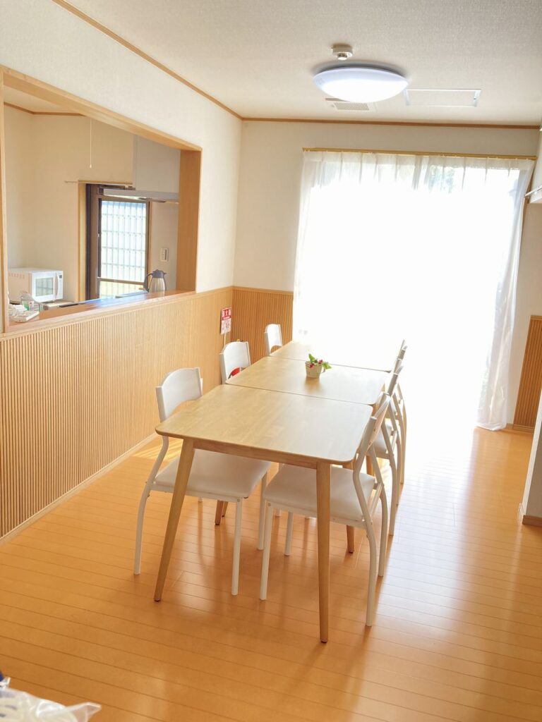 リビング中央にテーブルがあり、右に大きな窓がある日当たりの良い空間。天井には丸型LED照明と火災報知器が設置されている。